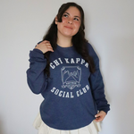 A person wearing an oversized blue crewneck that reads "Chi Kappa; Social Club" across the front with a picture of two pinkys intertwined. From Sierra Schultzzie.