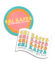 Two stickers, one is circular with a colorful, ringed background that says "Chi Kappa; Be confident. Be kind." The other is shaped like a flag with a white background with the words "Chi Kappa" repeated four times with "Social Club; Est. 2018" below it. From Sierra Schultzzie.
