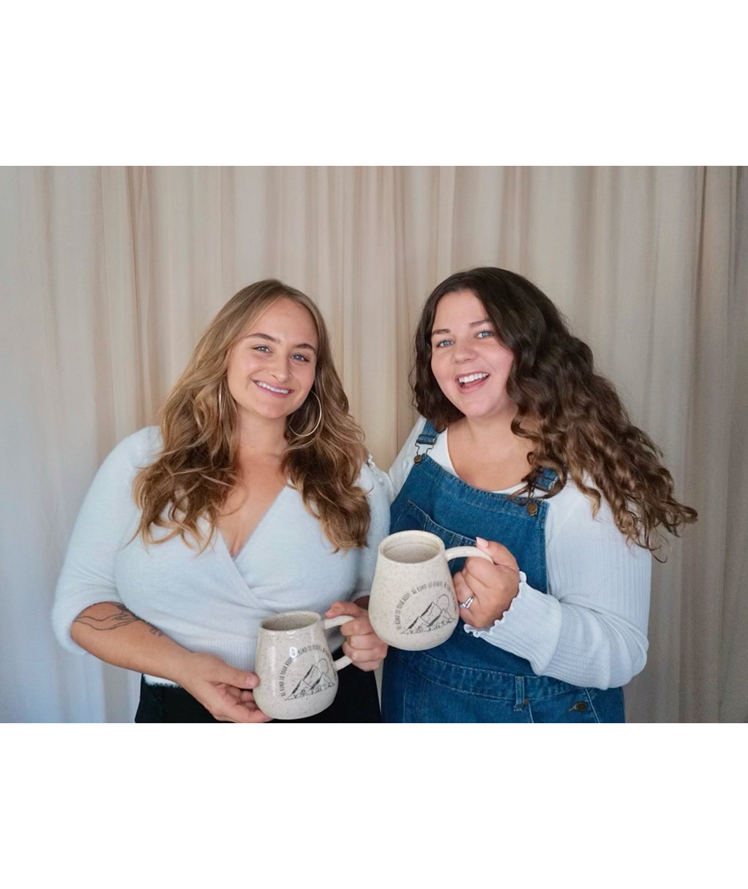 Sierra Schultzzie and a friend each holding the Be Kind mug. The mug is speckled beige with mountains and a moon. The text curves around the mountains and says "Be kind to your body be kind to others be kind to the planet".