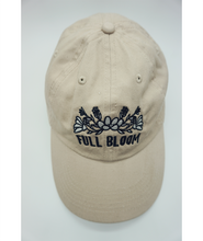 A top view of a beige ball cap with the embroidered words "Full Bloom" and flowers from Sierra Schultzzie.