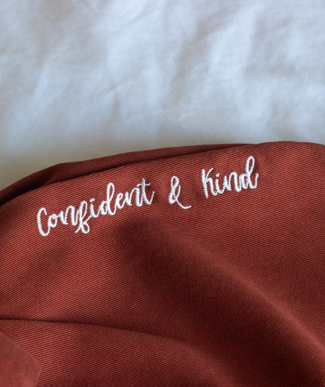Confident & Kind” is in white curisve font along the lefthand pocket of copper colored pants - from Sierra Schultzzie