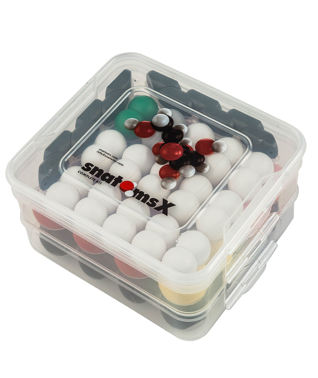 A clear, square plastic box full of various atom pieces arranged in rows. On the top of box is an image of a put-together molecule, and below that, the text "SnatomsX."