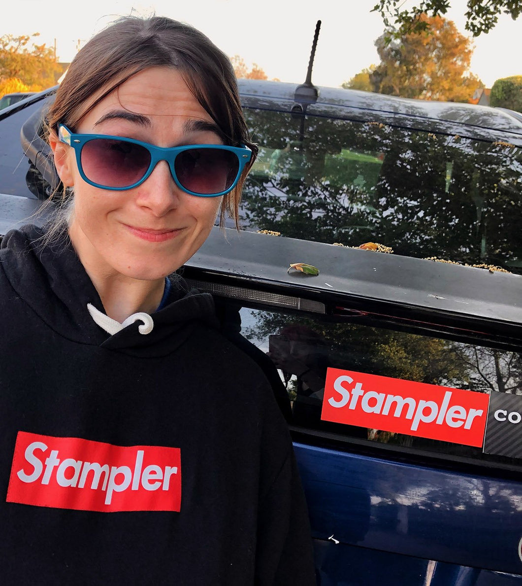 Beth May, Woman with. blue sunglasses, in the Stampreme hoodie in front of a car with the Stampreme bumper sticker.