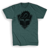A tealish green colored t-shirt with a centered large black illustration of a dragon's head peering at the pages of an open book, with a crest shape in the background. 