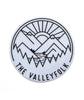 Circular sticker with black vector outline of mountains, a lake, trees, and a sun rising. “The Valleyfolk” is arched at the bottom in black sans serif font - from the Valleyfolk