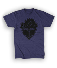 A heather dark purple t-shirt with a centered large black illustration of a dragon's head peering at the pages of an open book, with a crest shape in the background. 