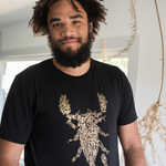 Tyler Thrasher modeling a dark gray shirt with white line drawn flowers arranged to make a scorpion in the center of the shirt - from Tyler Thrasher