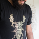 Tyler Thrasher modeling a dark gray shirt with white line drawn flowers arranged to make a scorpion in the center of the shirt - from Tyler Thrasher