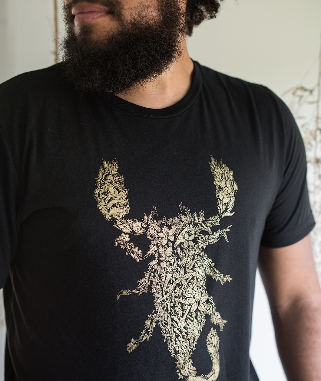 Tyler Thrasher modeling a dark gray shirt with white line drawn flowers arranged to make a scorpion in the center of the shirt - from Tyler Thrasher