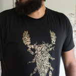 Tyler Thrasher modeling a dark gray shirt with white line drawn flowers arranged to make a scorpion in the center of the shirt - from Tyler Thrasher