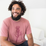 Tyler Thrasher modeling a red shirt with a dark red silhouette of a thistle weed in the center of the shirt. “Hands off” is written on the top of the thistle weed in red sans serif font - from Tyler Thrasher
