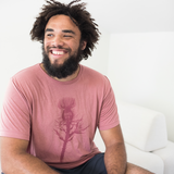 Tyler Thrasher modeling a red shirt with a dark red silhouette of a thistle weed in the center of the shirt. “Hands off” is written on the top of the thistle weed in red sans serif font - from Tyler Thrasher