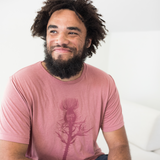 Tyler Thrasher modeling a red shirt with a dark red silhouette of a thistle weed in the center of the shirt. “Hands off” is written on the top of the thistle weed in red sans serif font - from Tyler Thrasher