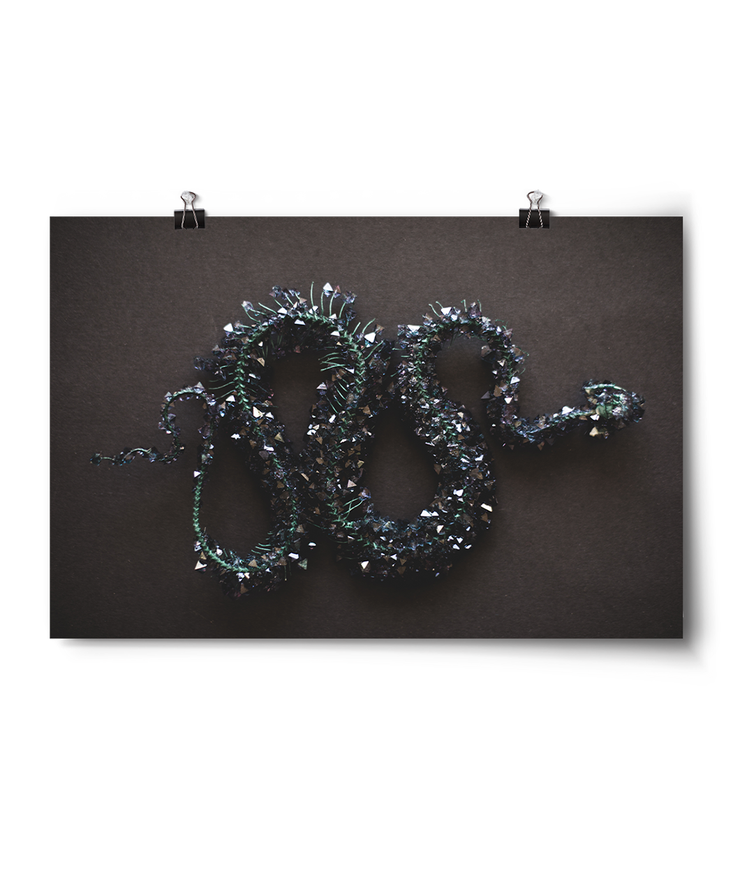 Horizontal print of a crystalized snake skeleton. Green and gold crystals cover entirely of skeleton that against a black background - from Tyler Thrasher