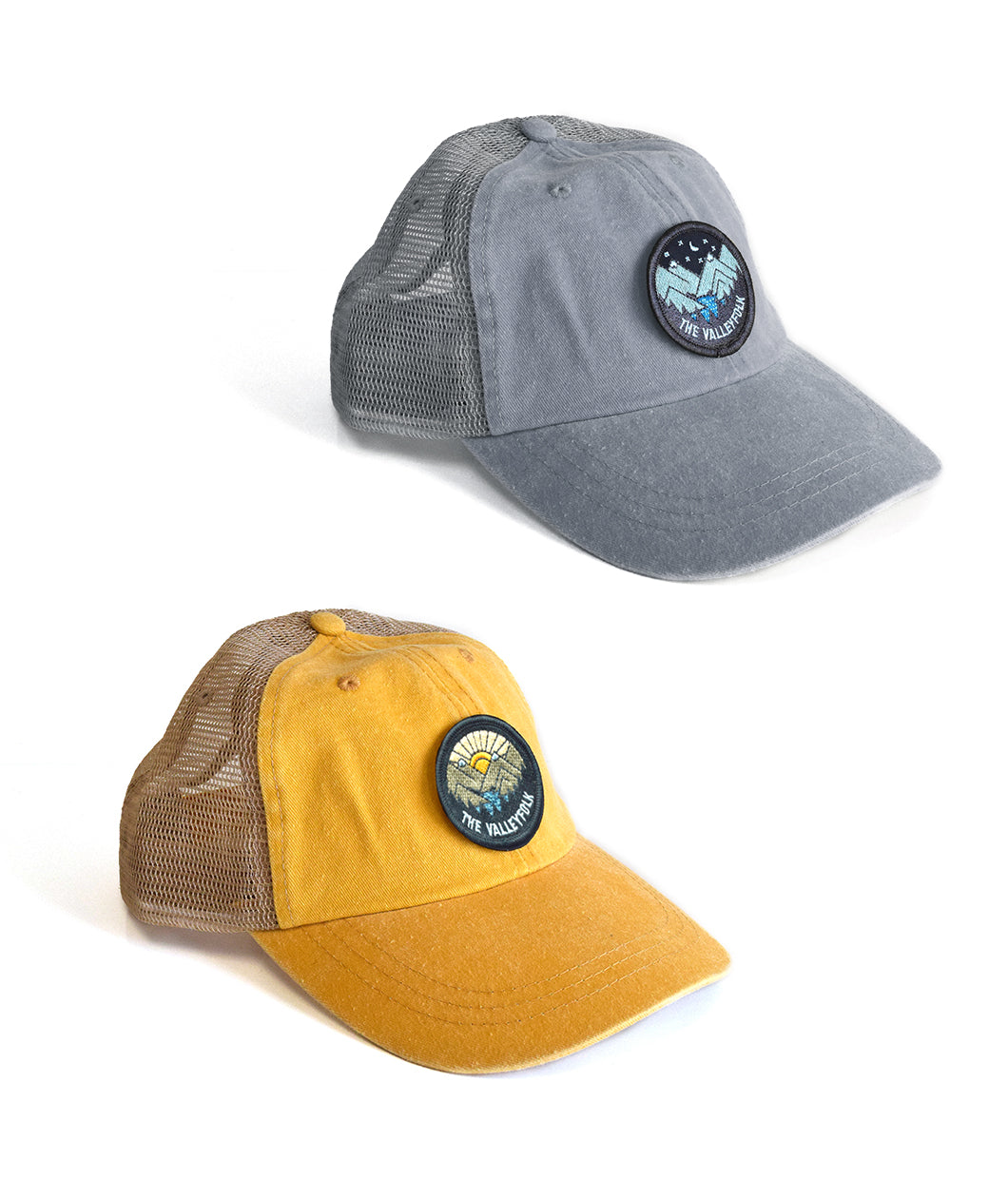 A yellow mesh hat with a patch in the center showing a vector drawn mountain scene with a sun rise in the background and “the Valleyfolk” arched along the bottom. A gray mesh hat with a patch showing a nighttime vector mountain scene with “the Valleyfolk” arched along the bottom - from the Valleyfolk