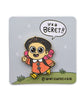 Enamel pin of a young girl mid stride. The girl is wearing an orange coat, a black beret, yellow rainboots, and has pink hair. The pin is on a backing card that says "@whatsupbeanie" and has a word bubble that says "It's a BERET!!"