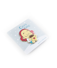  A pin of Beanie closing their eyes, with a smile holding a big mug of coffee with a heart on the front of the mug. The pin is on a card backing with falling snow and the words "Cozy Time; @whatsupbeanie".